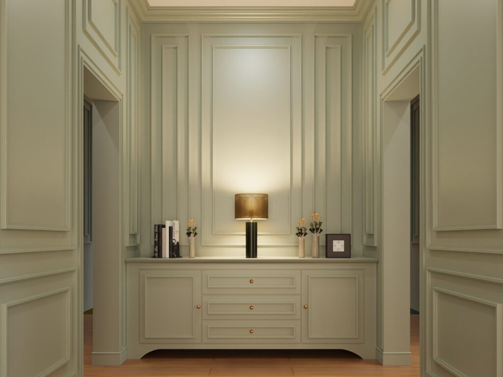 stylish room with green walls, detailed molding, a console table with a lamp, and decorative items.