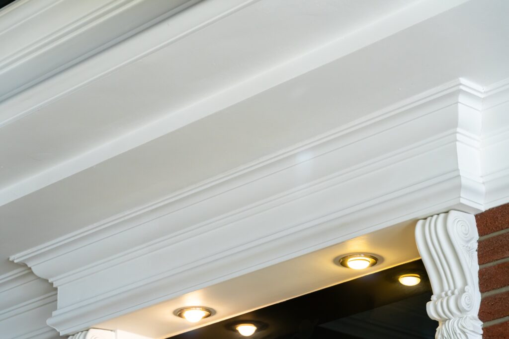 A detailed view of white decorative molding with recessed lighting underneath.