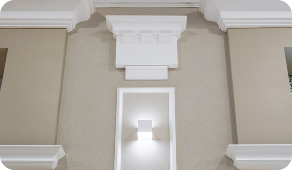 A detailed view of decorative molding with recessed lighting on a textured wall.