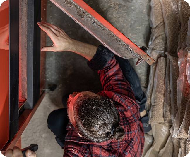 A person crouching and inspecting or repairing machinery, seen from above.