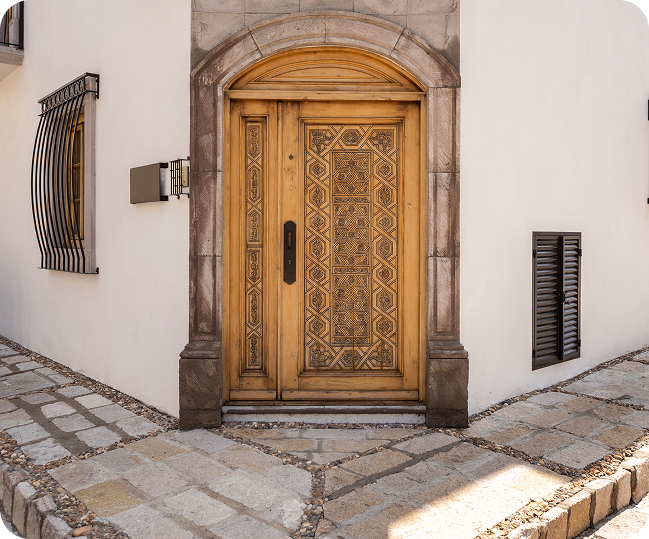 beautifully carved wooden double door with intricate designs, leading into a home,