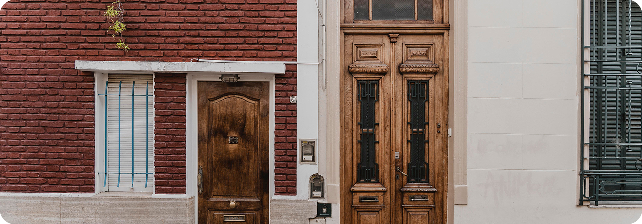 Two elegant entry doors made of wood, with detailed carvings and glass inserts