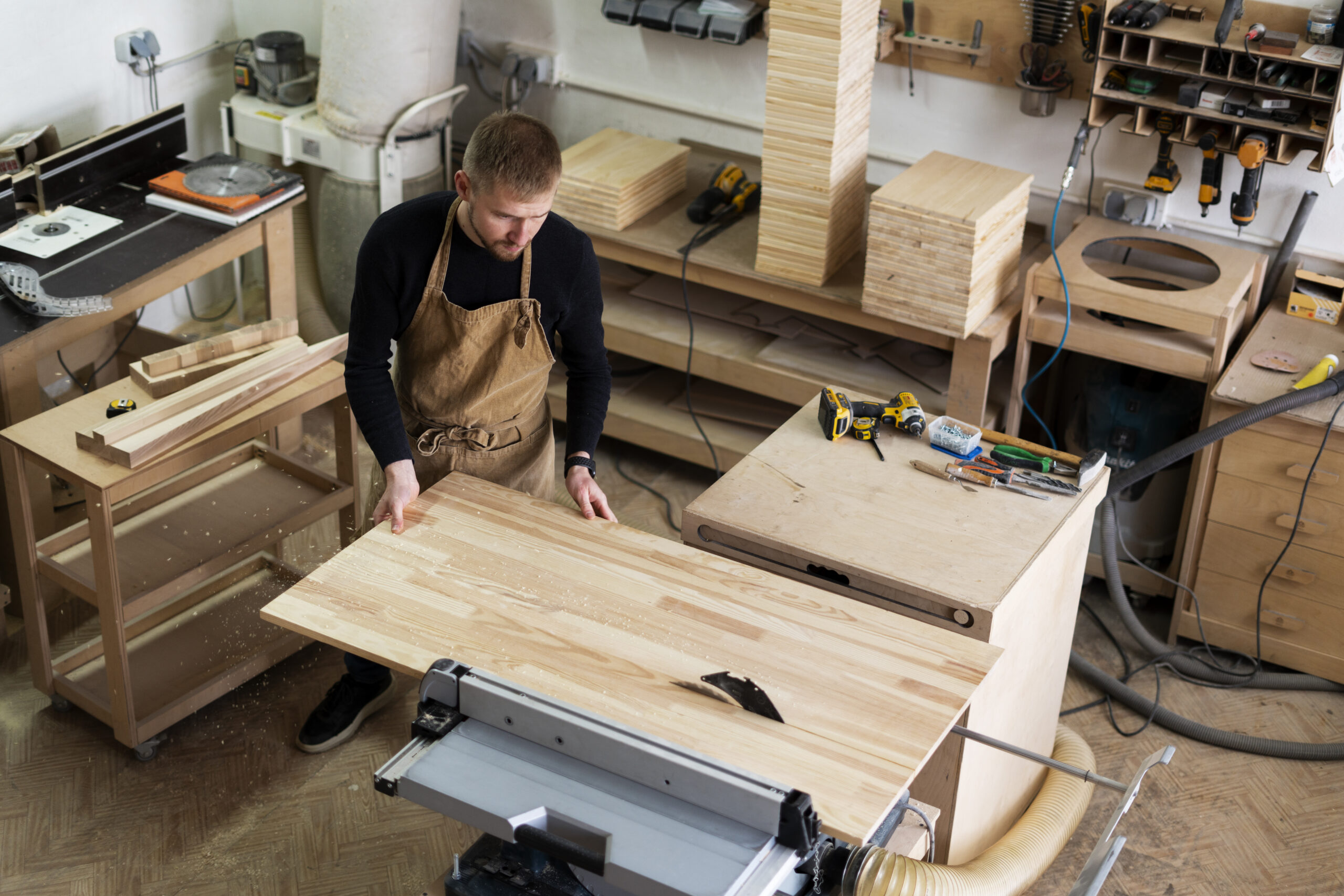 Craftsman working on custom wood millwork in a workshop with tools and materials